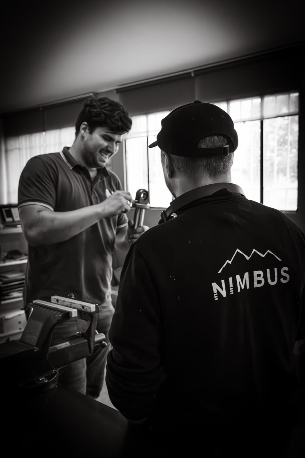 Two Nimbus builders discussing a suspension component in the workshop
